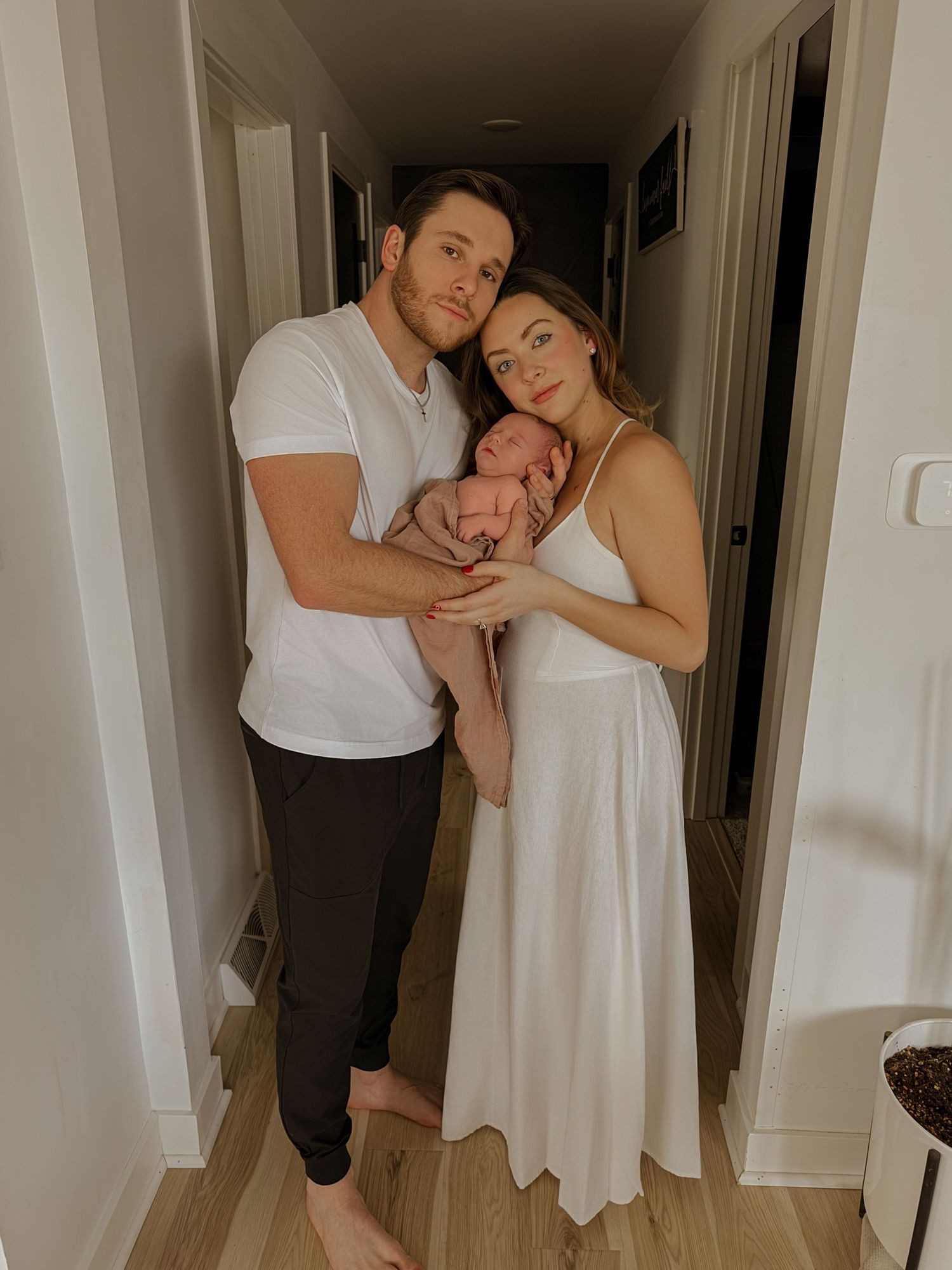 Intimate family moment captured in hallway with soft lighting.
