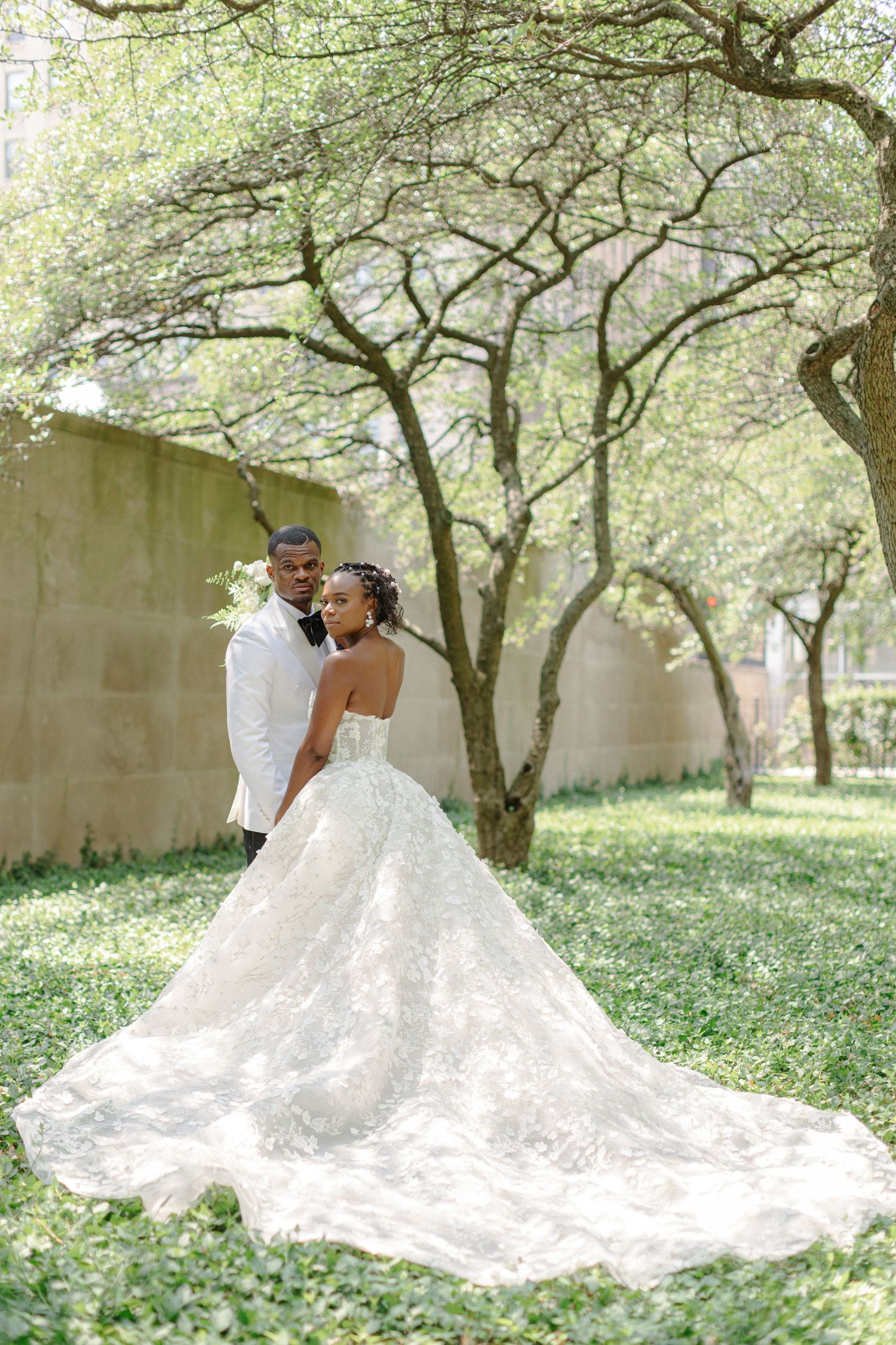Romantic wedding portrait under spring trees with bride's flowing lace gown.