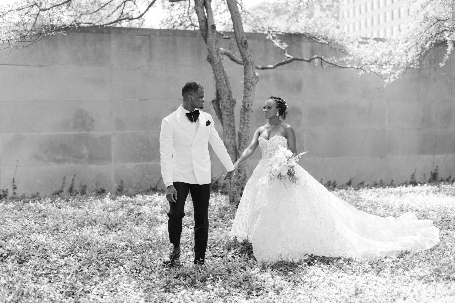 Wedding couple shares intimate moment in garden setting with dramatic train.