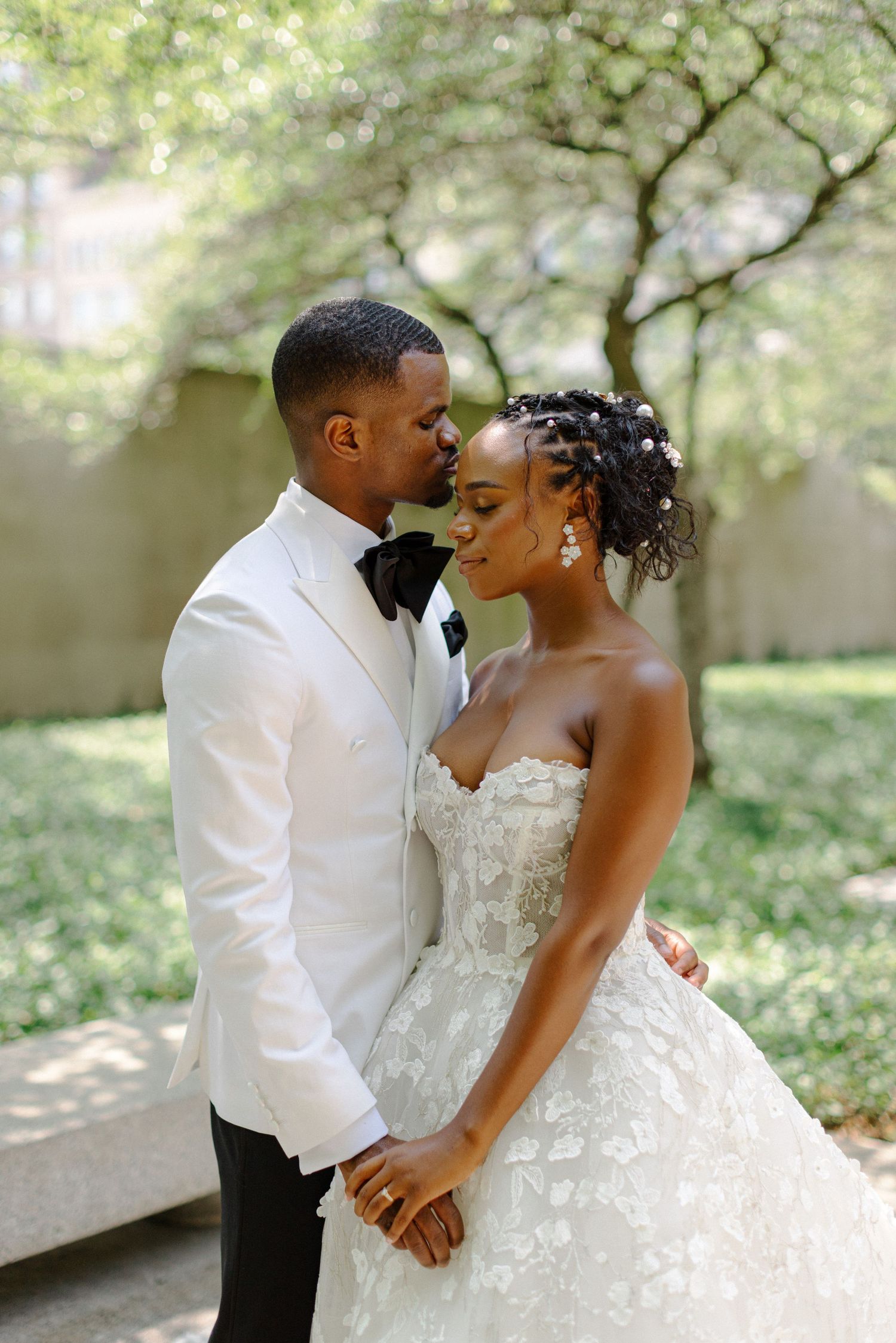 A romantic wedding portrait shows the couple embracing in a lush garden setting.