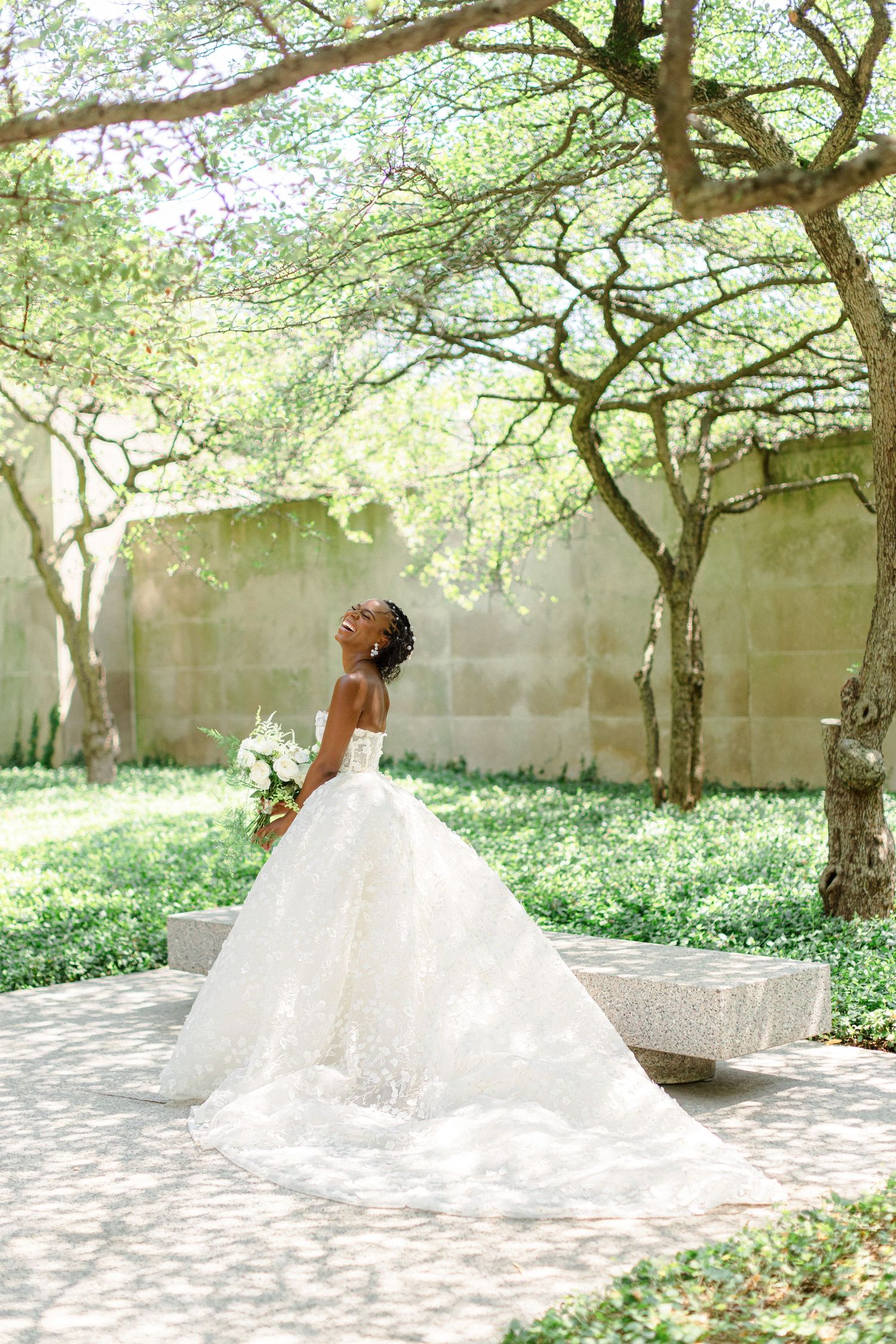 A beautiful wedding dress with a dramatic train photographed in a garden setting.