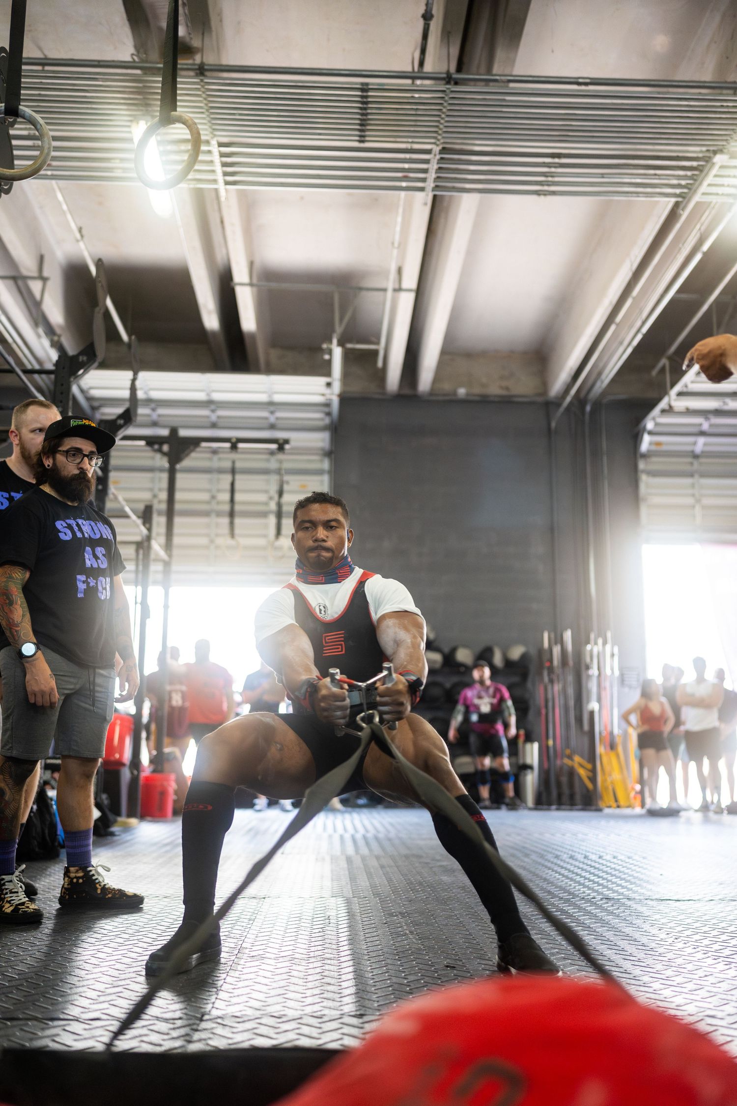 Powerlifter in competition gear preparing for lift with spectators watching in background.