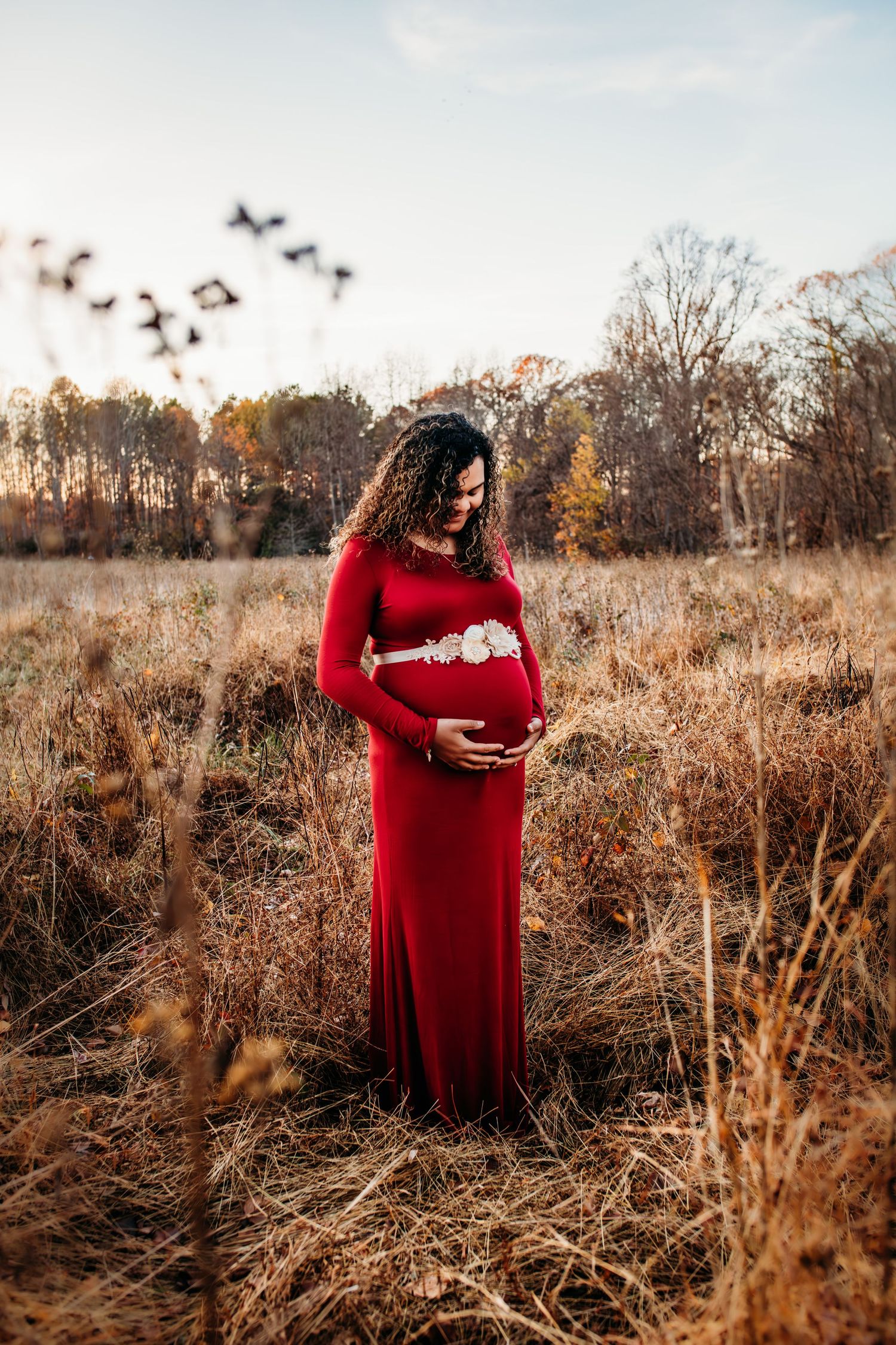 Maternity picture of woman in field holding her belly. Captured by Maryland Photographer Mallory Bramlett.