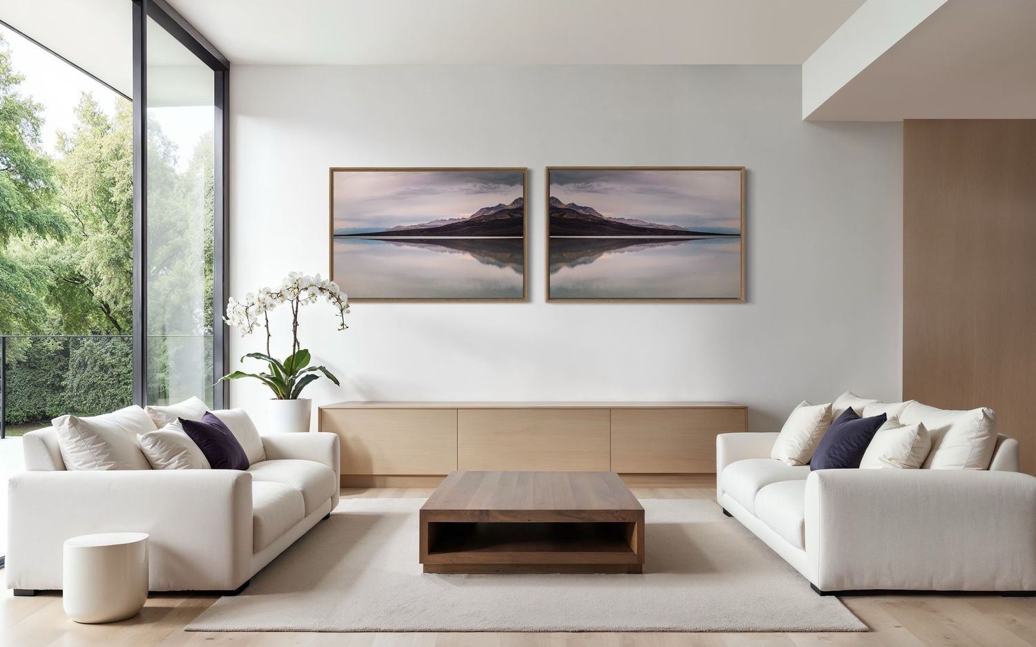 Modern minimalist living room with white sofas, wood coffee table, and landscape artwork.