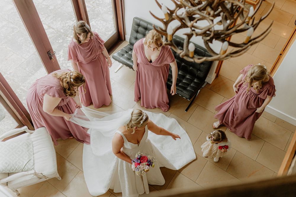 Overhead view of wedding preparation with bridesmaids in dusty rose dresses.