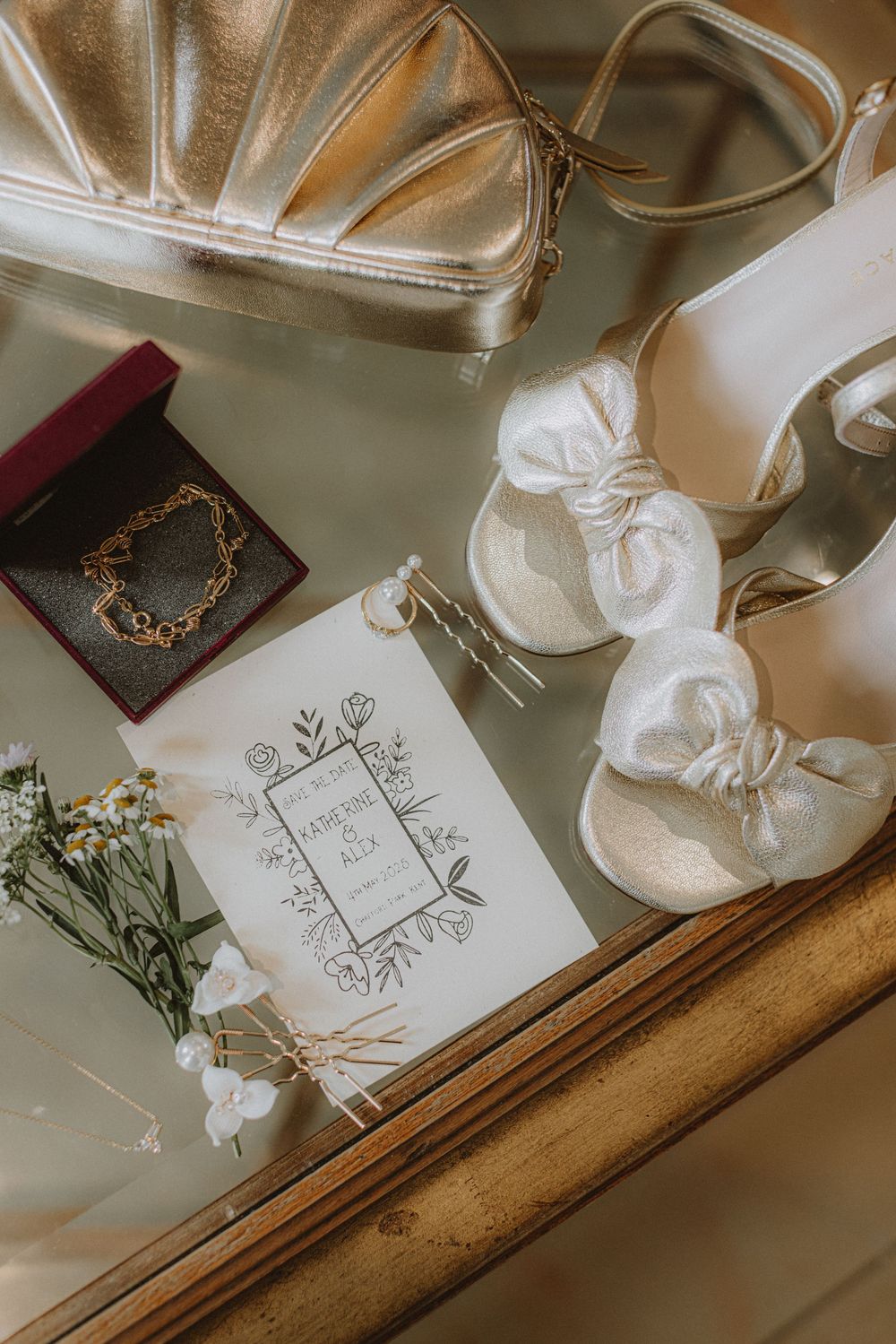 Wedding accessories including white shoes, invitation cards, and delicate floral details arranged on a surface.