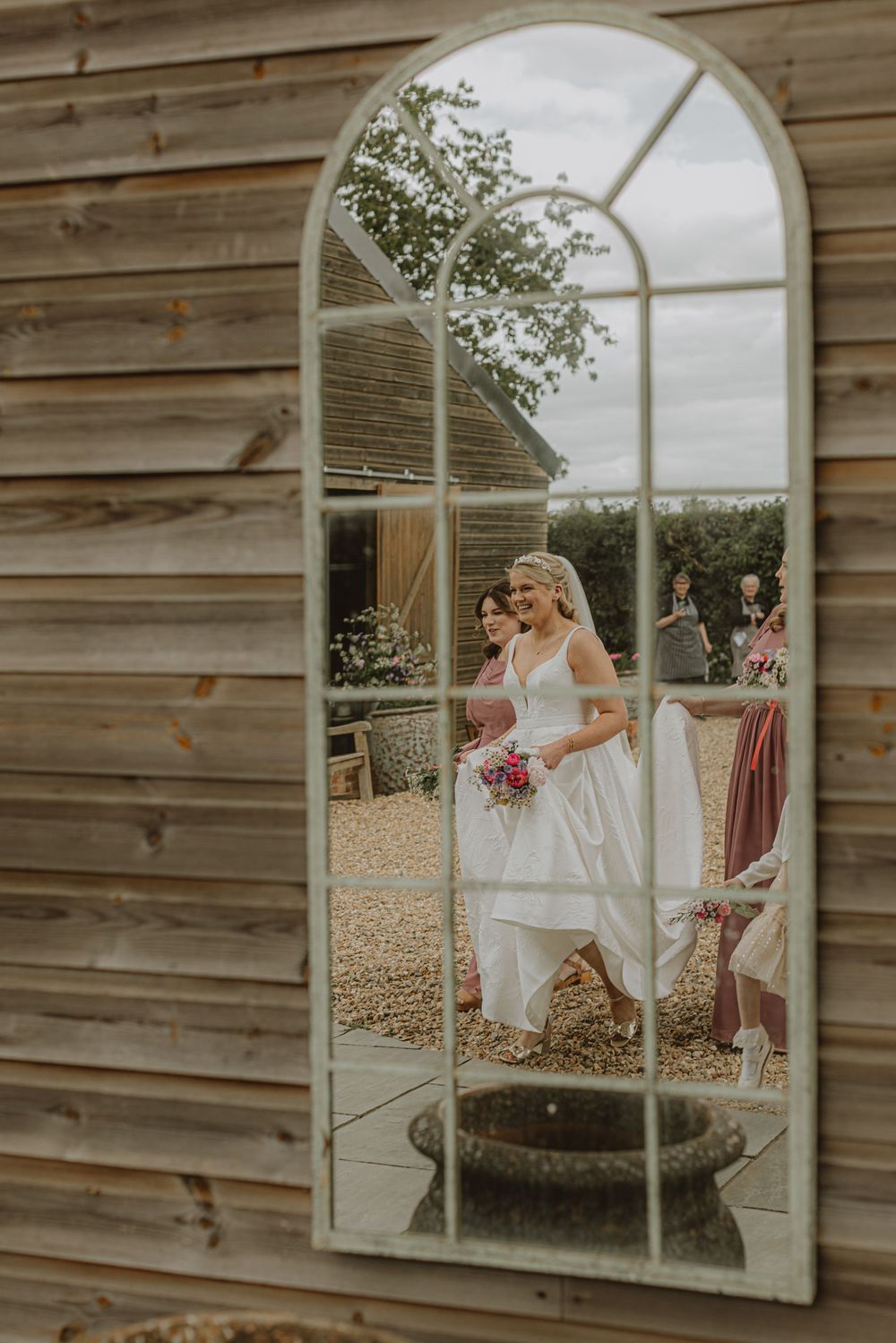 Rustic wooden wall with mirror reflecting wedding party members.