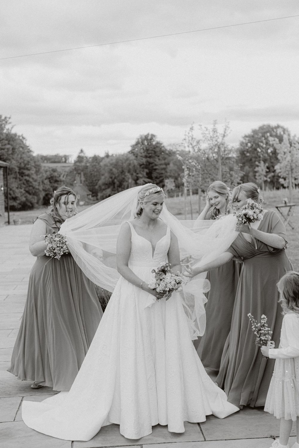 Wedding party poses together outdoors in white and sage colored dresses.