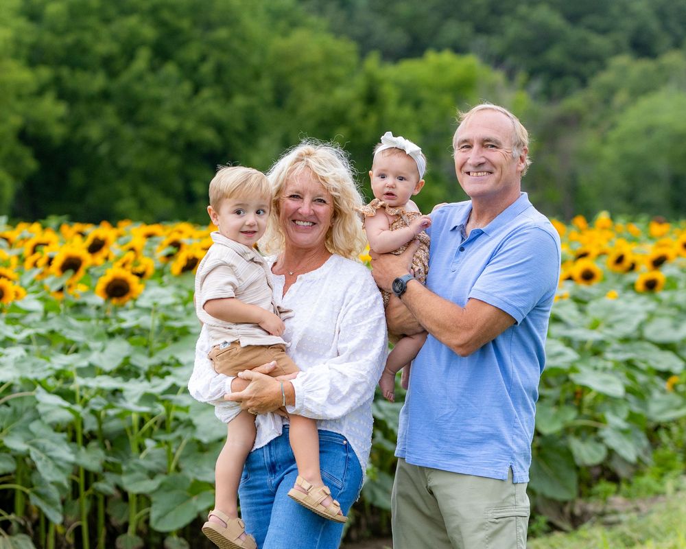 Extended family poses together during a family photo session in a sunflower field at Verrill Farm in Concord, MA by Lisa West Photography.