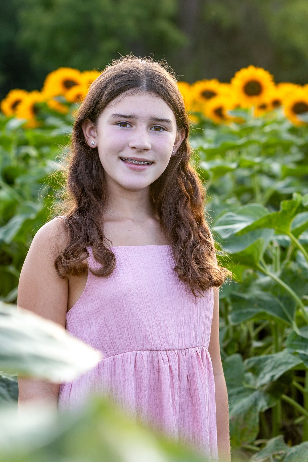 A young lady poses during a family photo portrait session in a sunflower field at Verrill Farm in Concord, MA by Lisa West Photography.