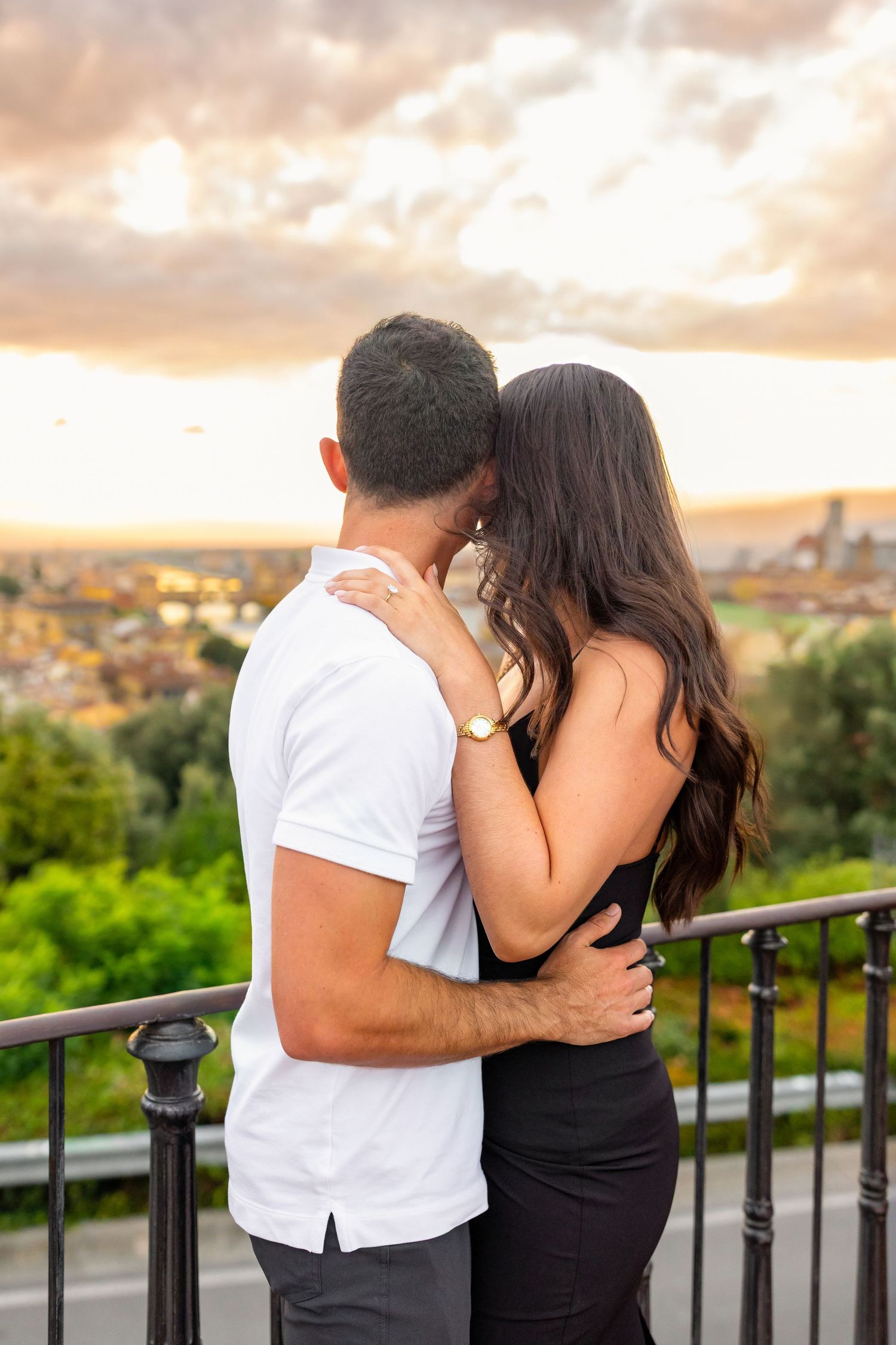 Couple sharing intimate moment against sunset cityscape backdrop.