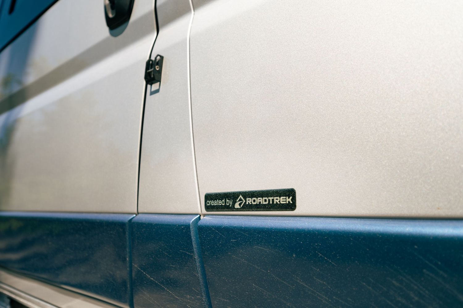 White car door detail showing panel molding and lines against a light-colored interior background.