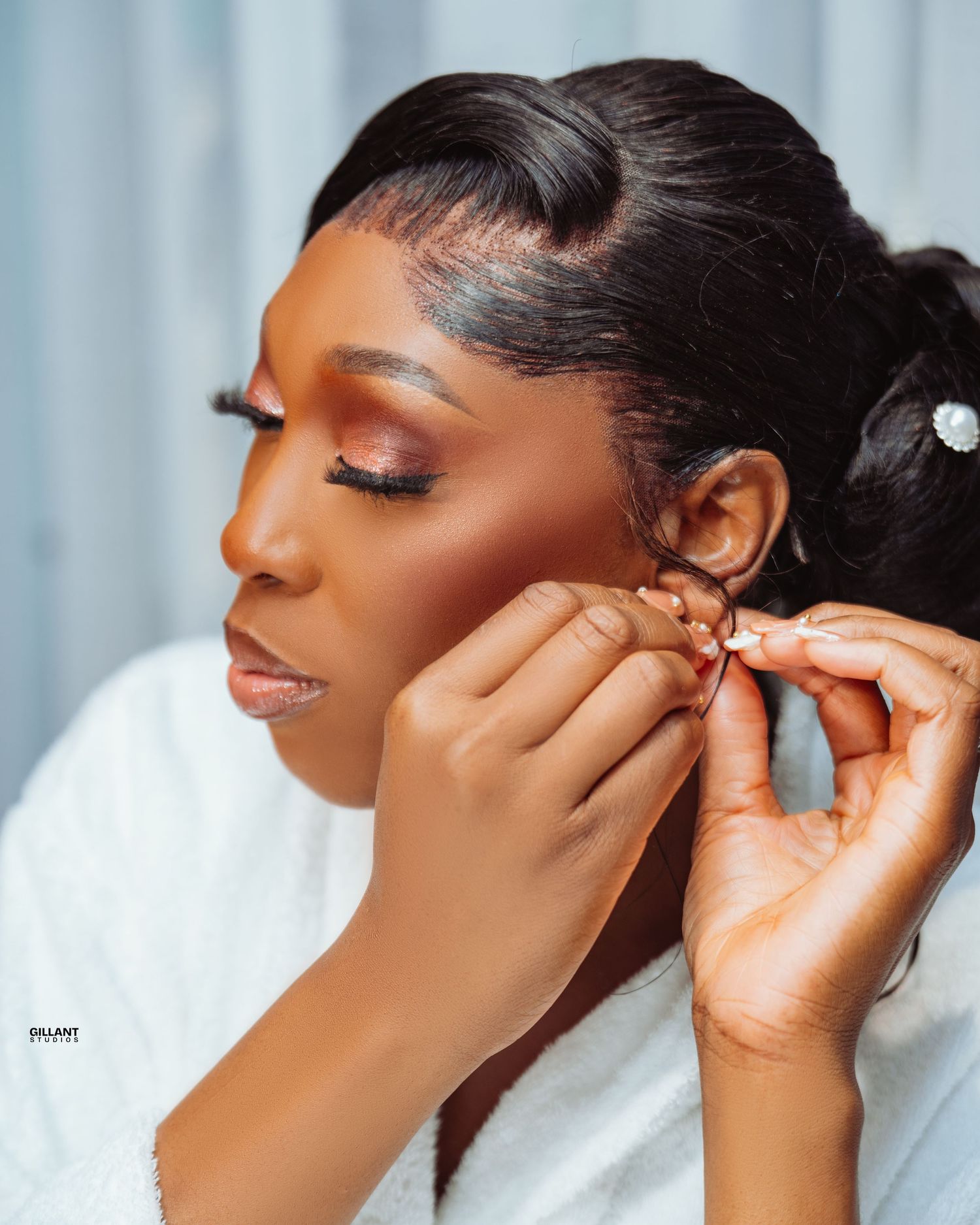 Close-up shot of hands putting on earrings during bridal preparation.