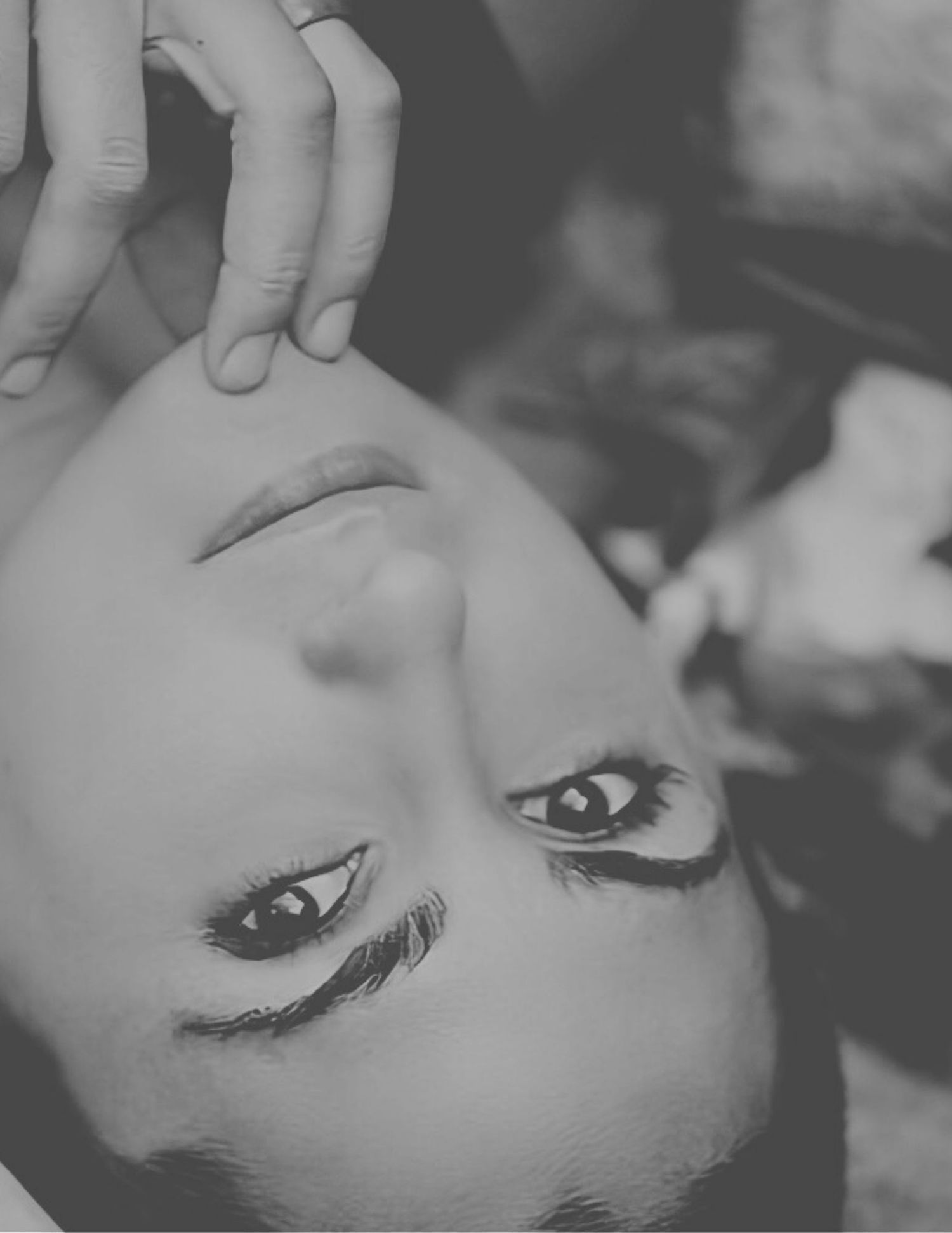 A dramatic black and white photo of someone looking downward from a sideways angle with long eyelashes visible.
