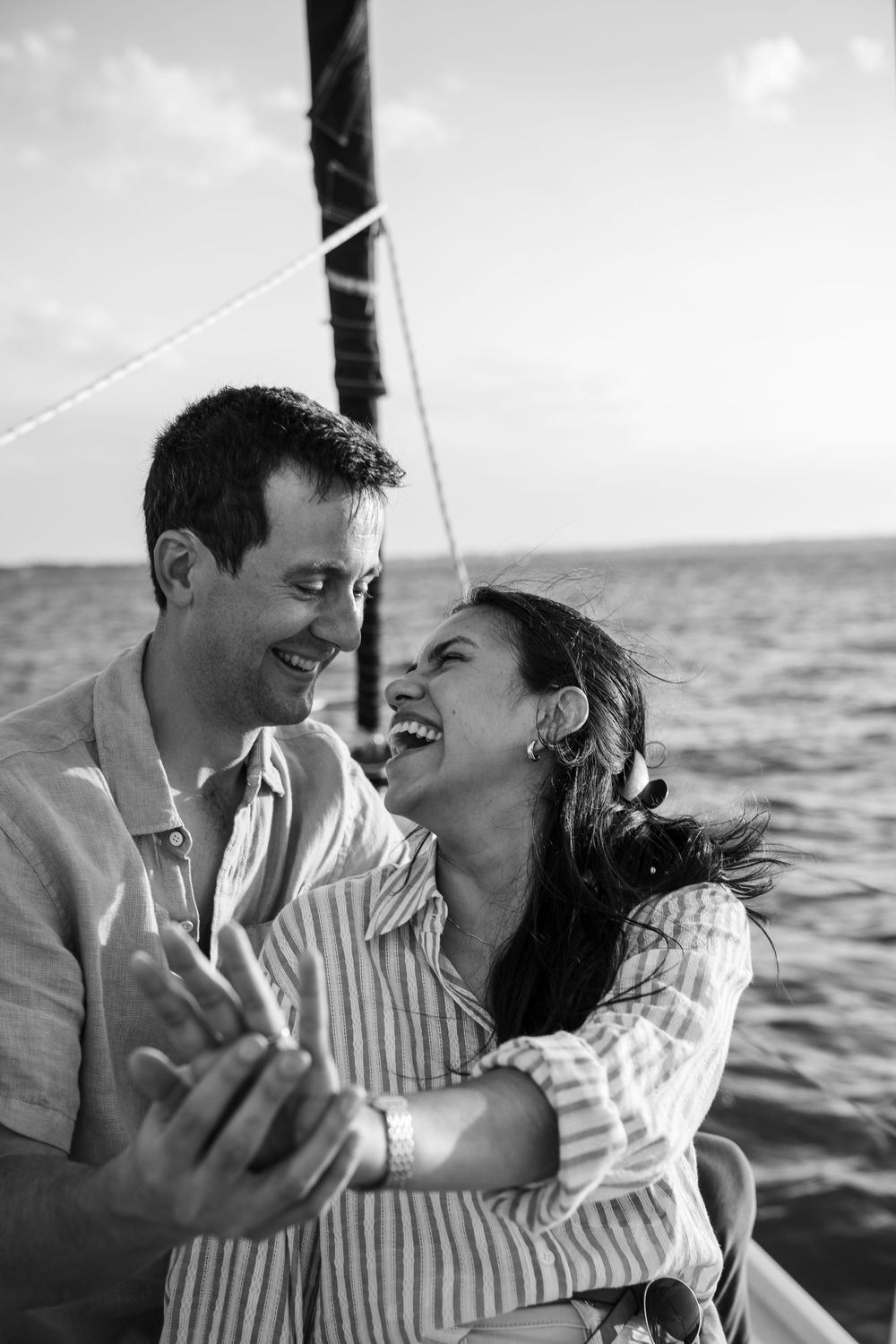 A romantic black and white moment shared between a couple laughing together while sailing on the ocean.