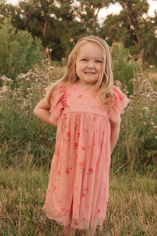 Westminster family photographer captures joyful little girl's bright smile in pink dress surrounded by meadow wildflowers