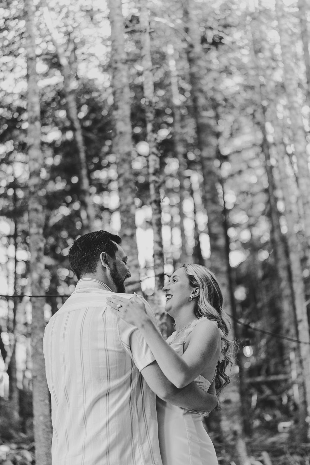 A romantic couple shares an intimate dance together in a serene forest setting.