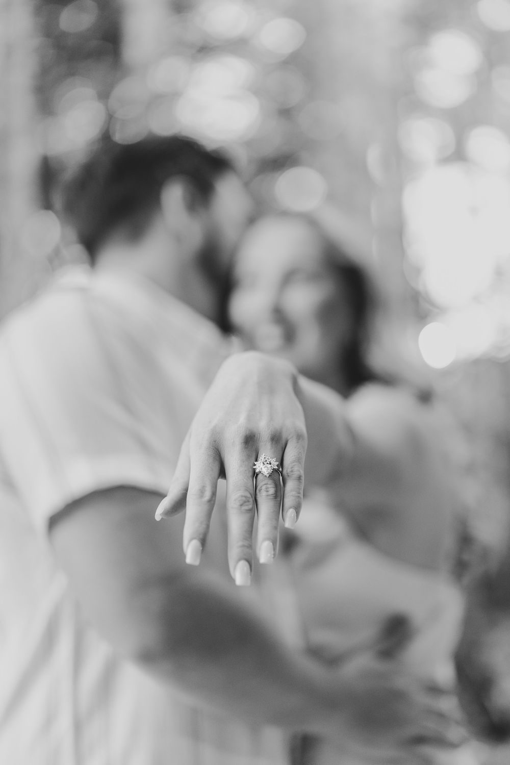 Hands with wedding rings shown in soft focus black and white photography with bokeh background effect.