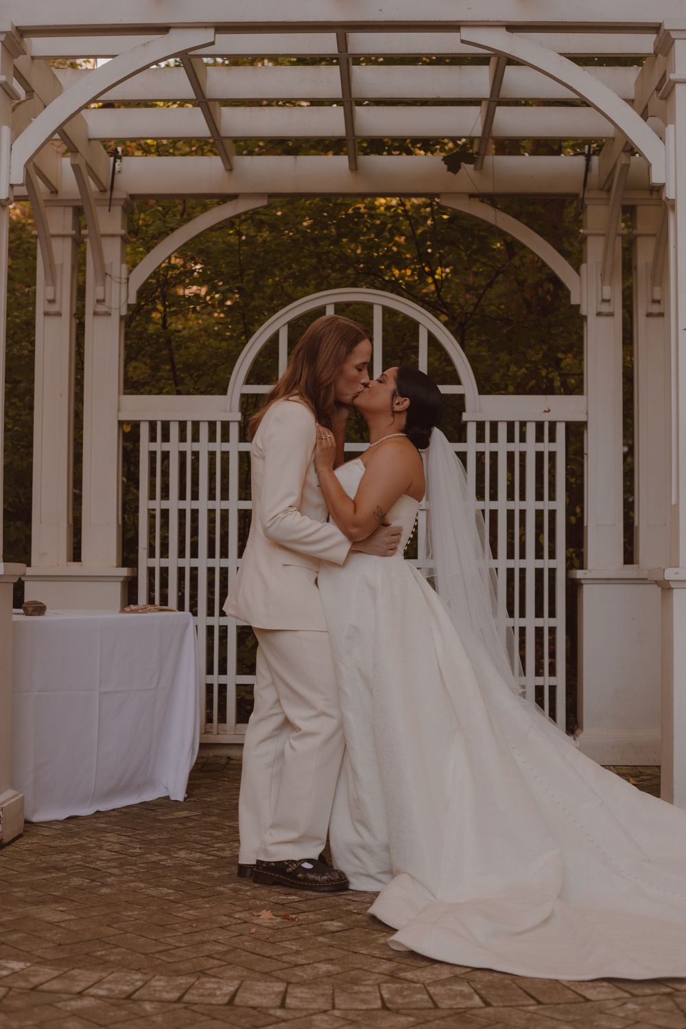 LGBTQ+ wedding photographer. Brides share a romantic kiss at the altar.