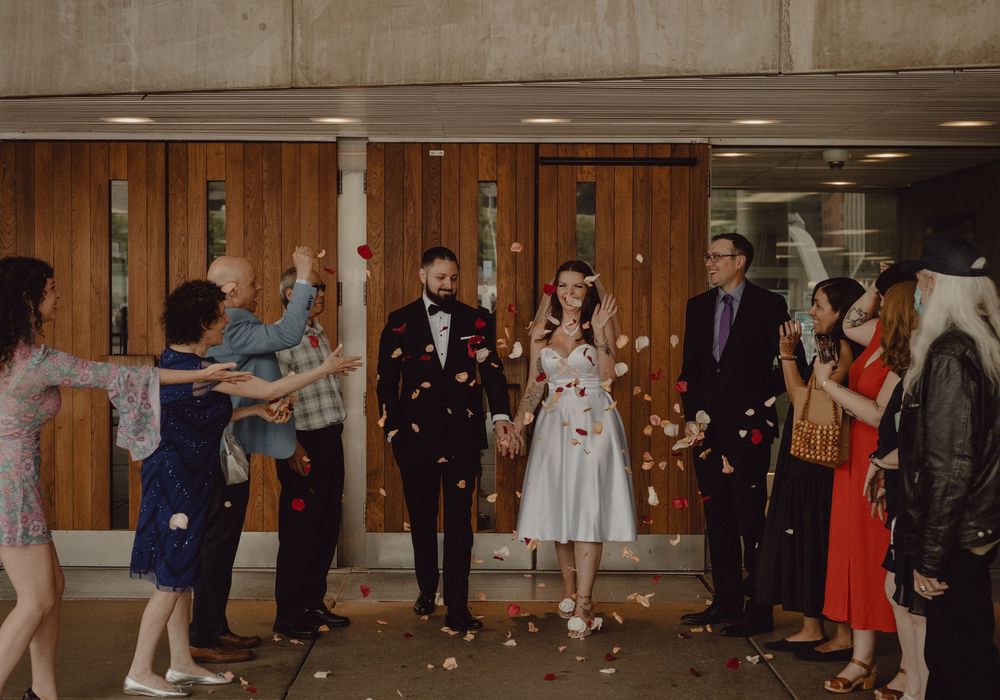 Bride and groom leaving city hall shortly after their vows while their closest family & friends celebrate with rose pedals. Toronto