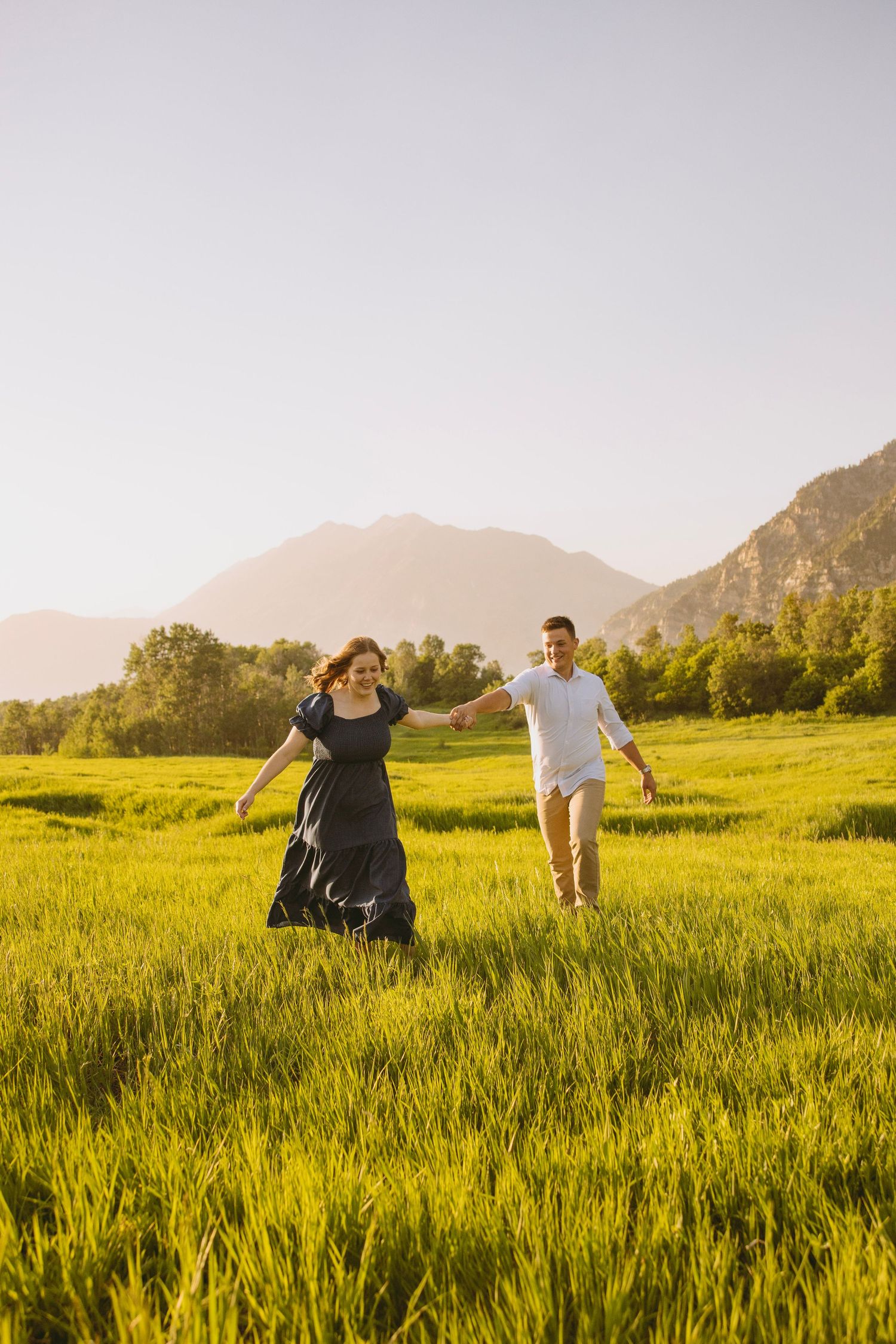 A couple shares an intimate moment along a forest path lined with evergreen trees and birch during a wedding photo session.