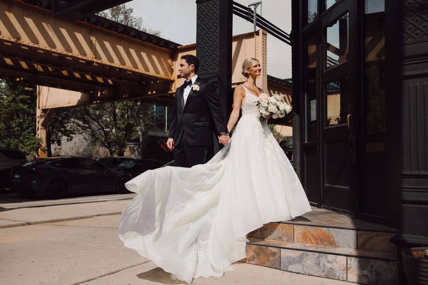 Elegant urban wedding photos with flowing white dress against modern architecture.