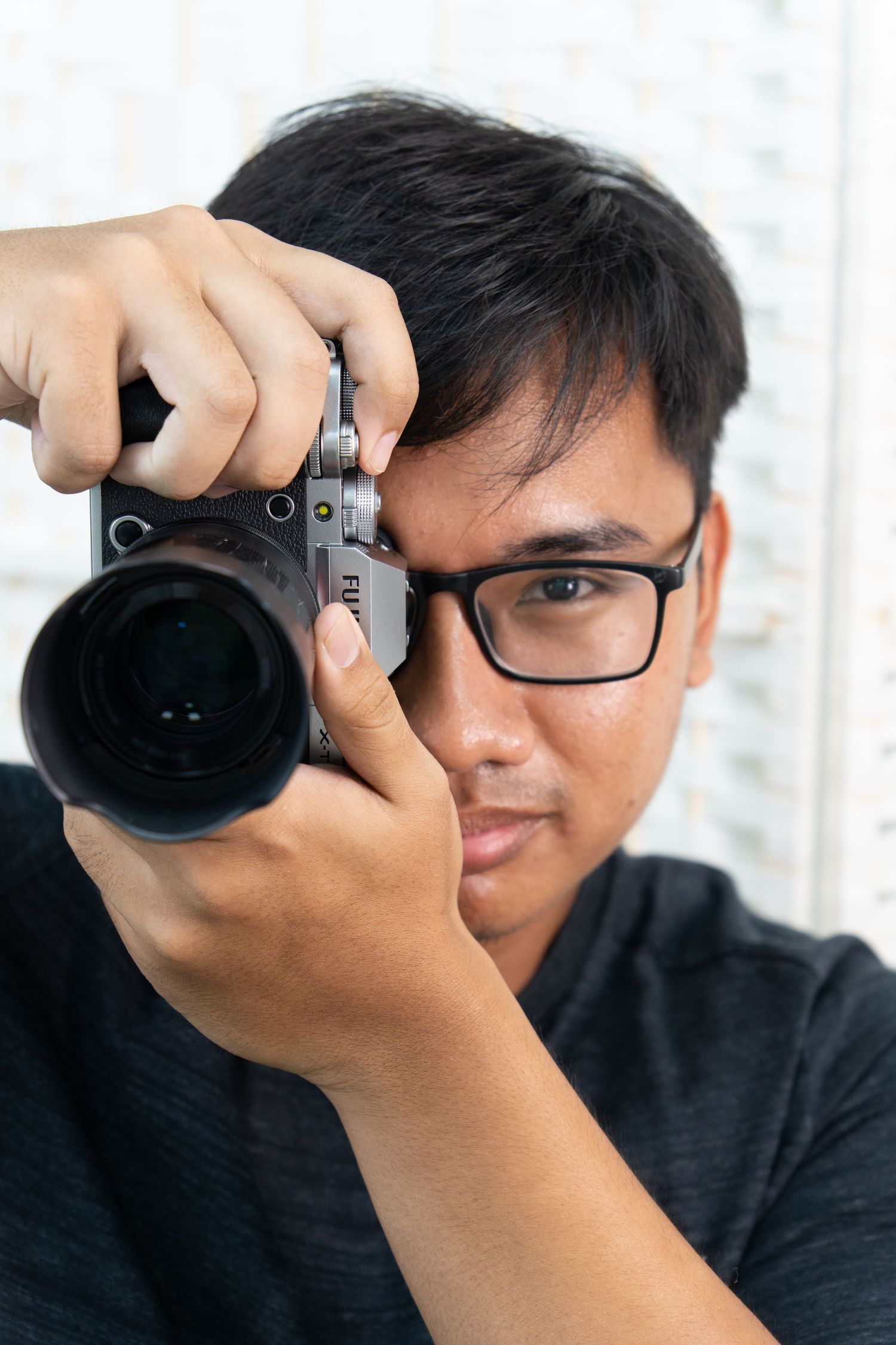 A photographer in black clothing holds up a camera to take photos from multiple angles.