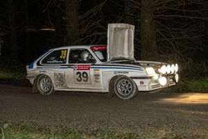 Ford Escort rally car number 39 with open bonnet competing on a night forest stage.