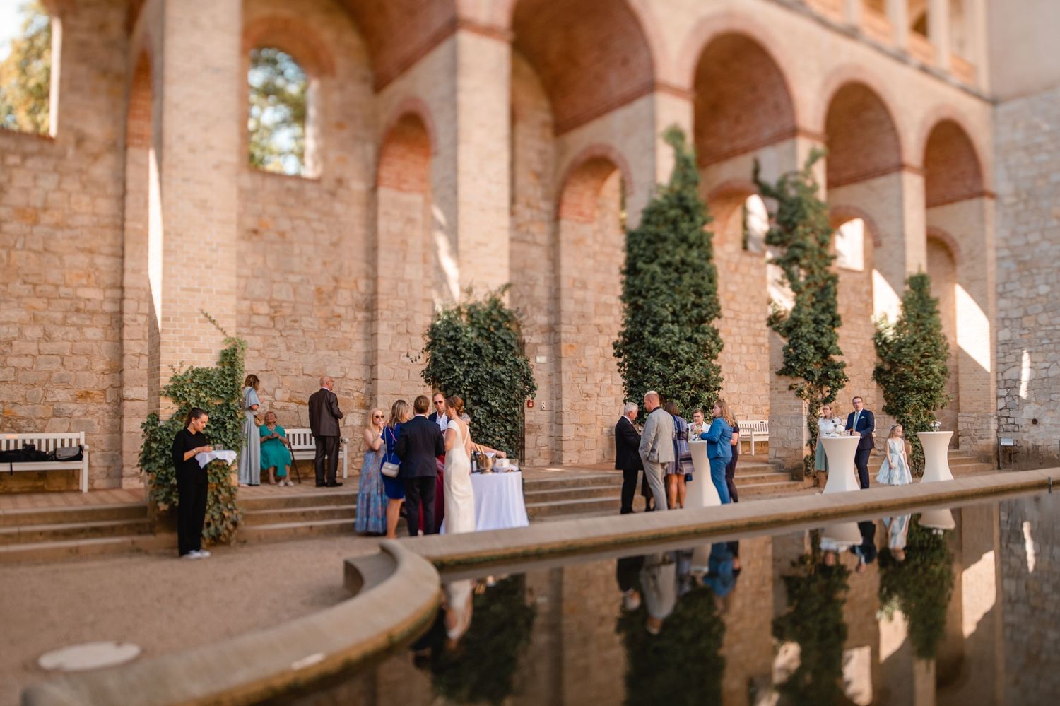 Wedding ceremony takes place in an elegant arched room with checkerboard floor and ornate architecture.