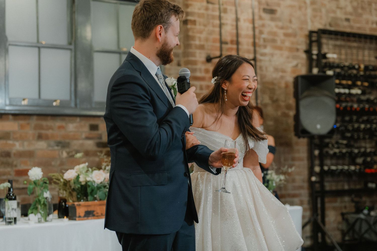 Wedding party enjoying candid moments in an industrial-style venue with exposed brick walls.