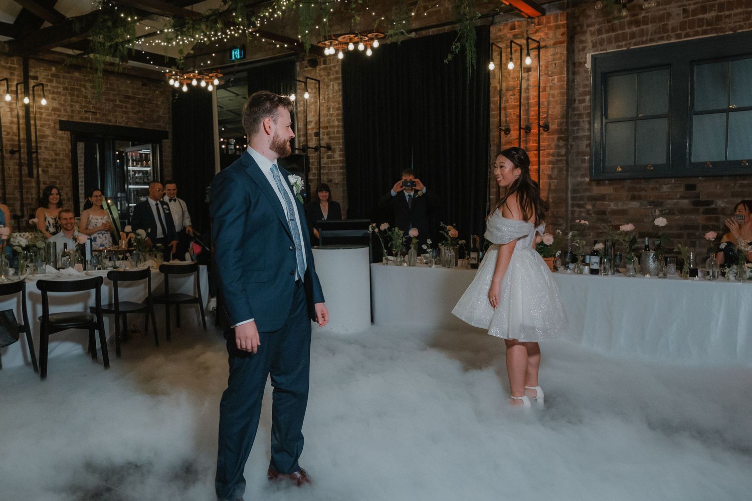 Wedding reception setup in modern industrial venue with exposed brick and minimalist decor.
