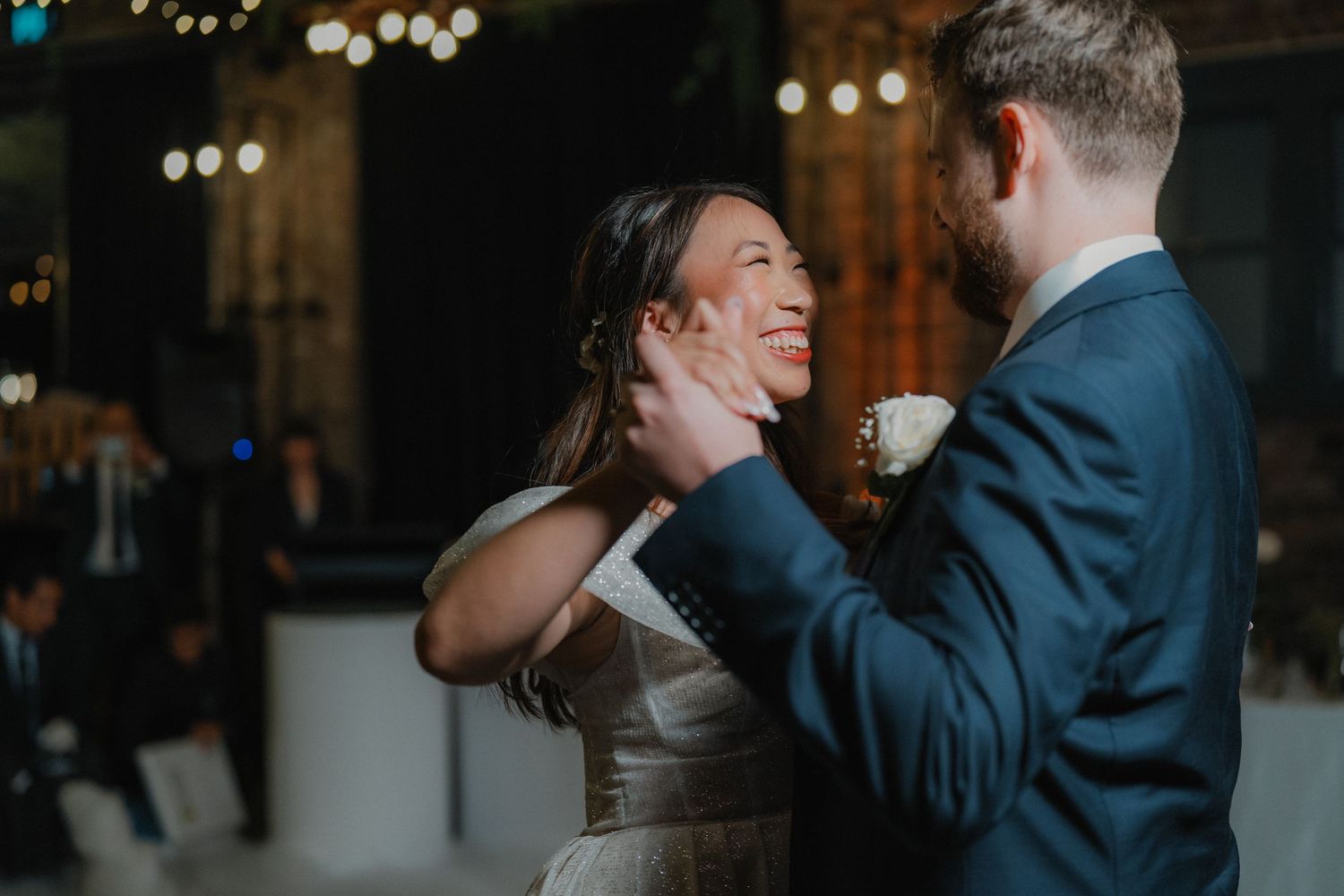 Couple sharing an intimate dance moment under twinkling lights at their wedding reception.