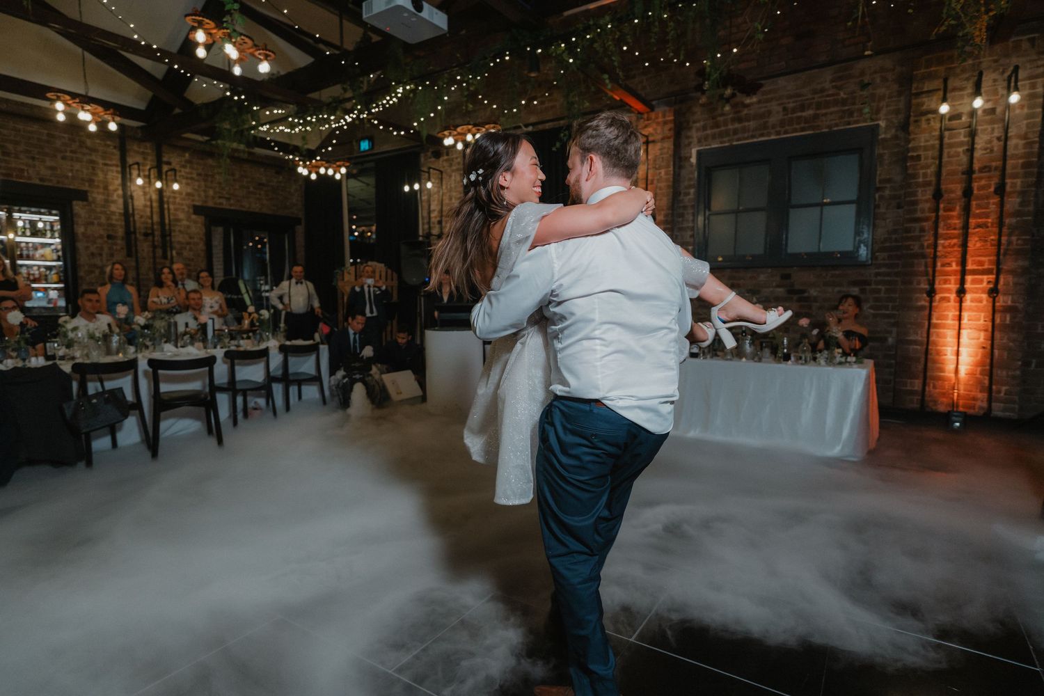 First dance with fog machine effects in industrial chic wedding reception venue.