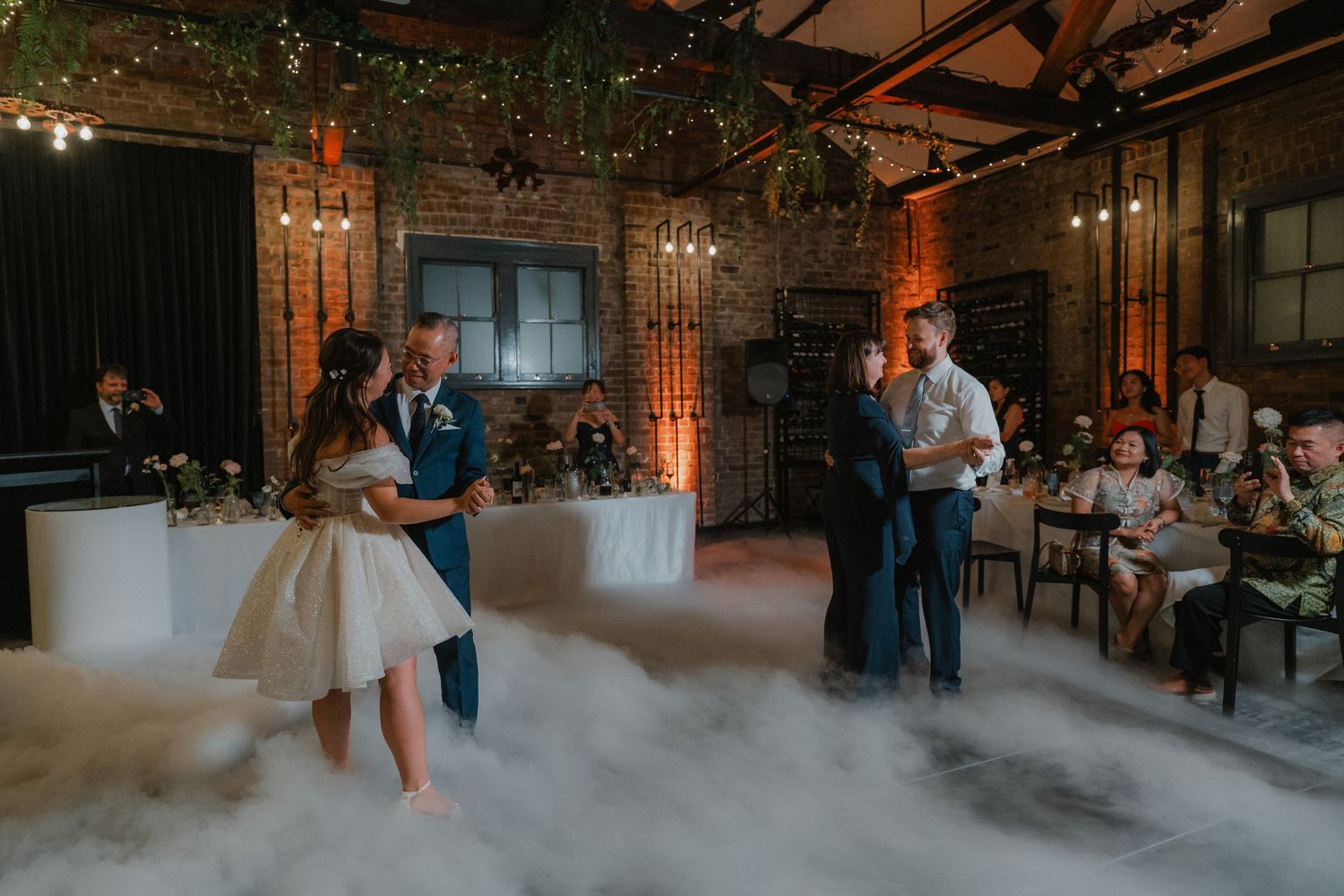 Wedding reception dance floor with fog effects and mood lighting in an industrial brick venue.