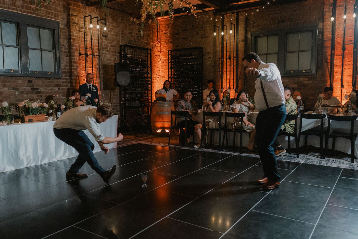 Dance floor with atmospheric fog effects during wedding reception in brick-walled venue.