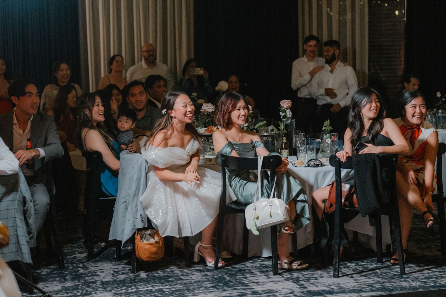 Wedding guests seated at reception tables watching entertainment performance.