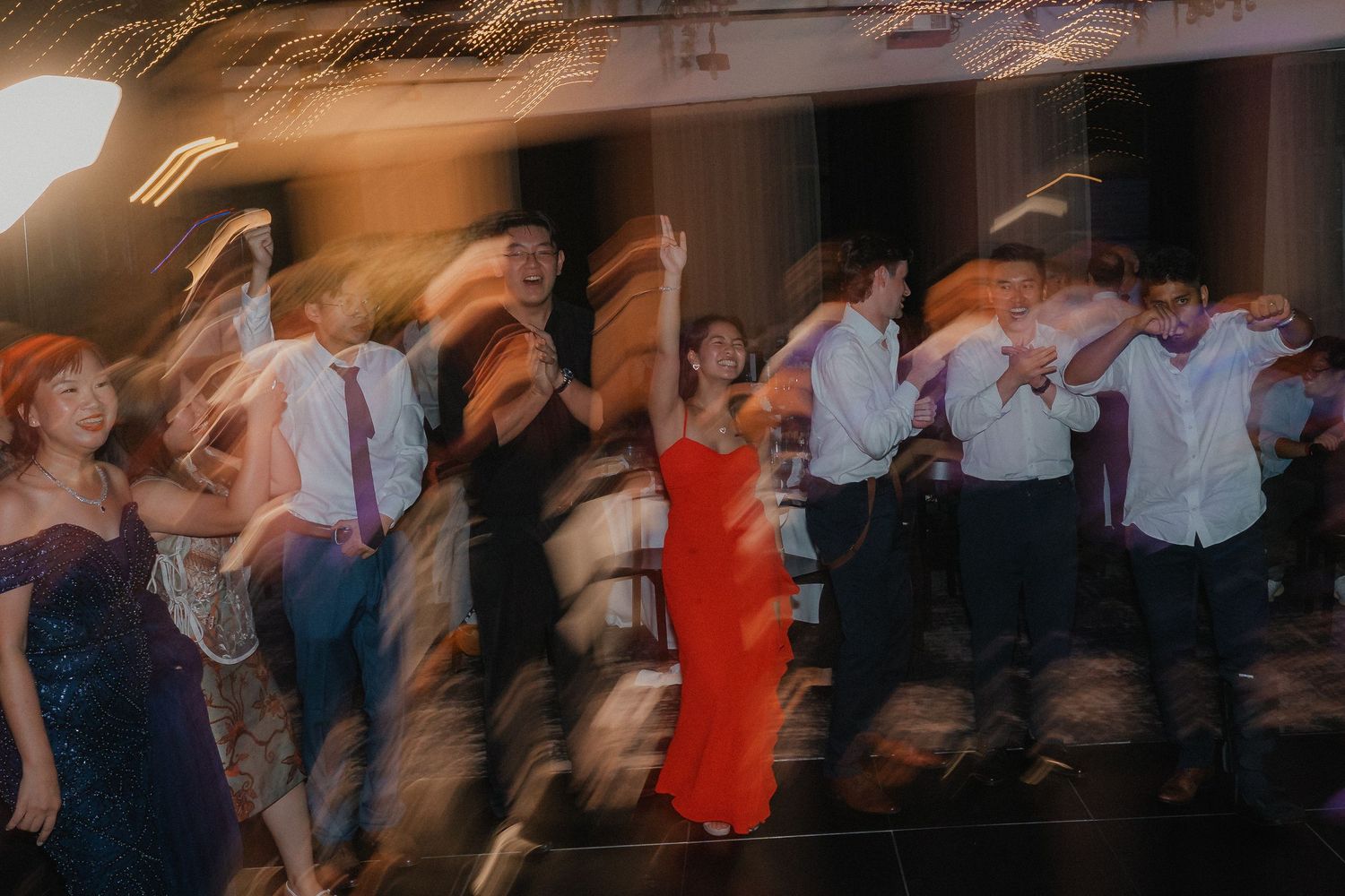 Motion-blurred photo of wedding guests dancing energetically on the dance floor.