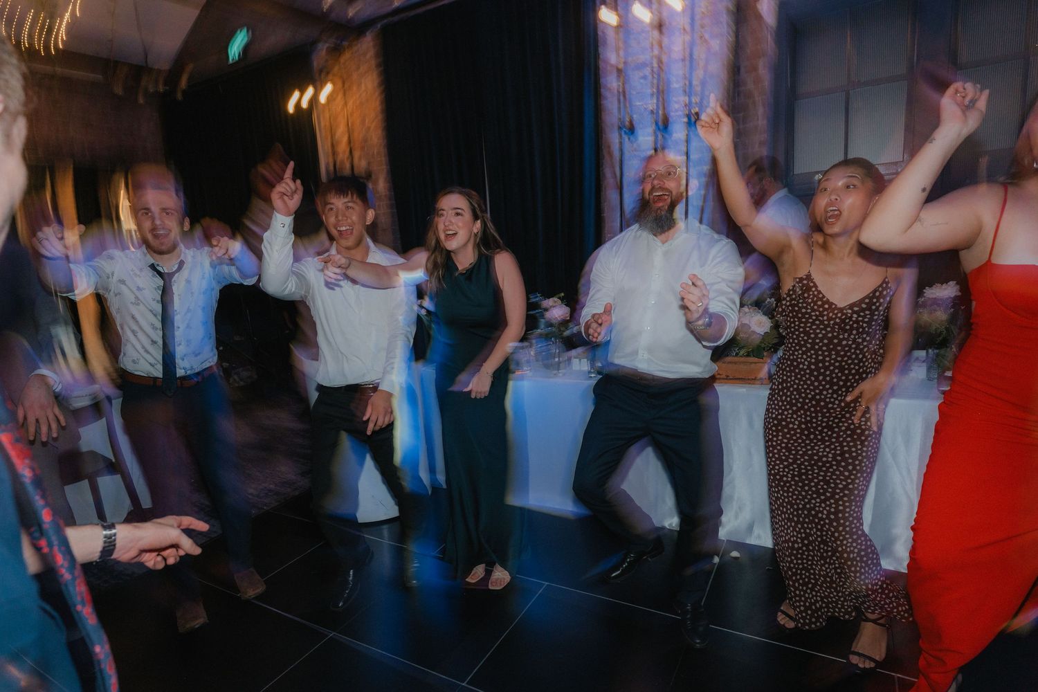 Dancing guests enjoying themselves on a dimly lit dance floor at a celebration party.