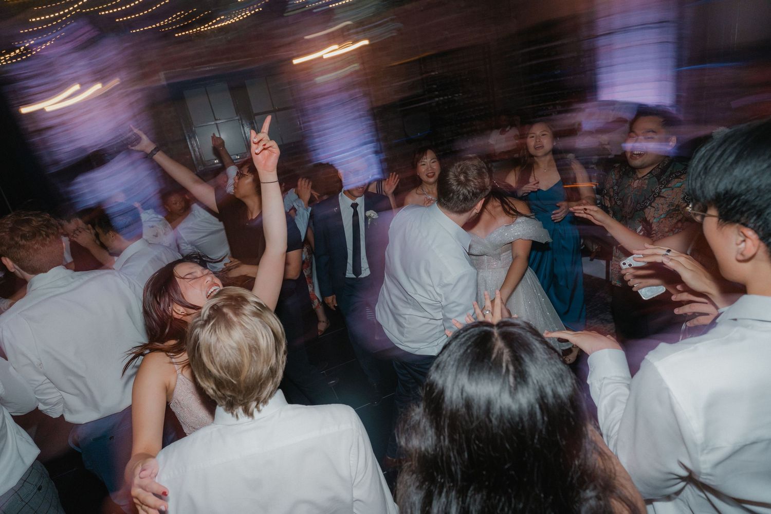 Crowd of people dancing energetically at a party with motion blur and atmospheric lighting effects.