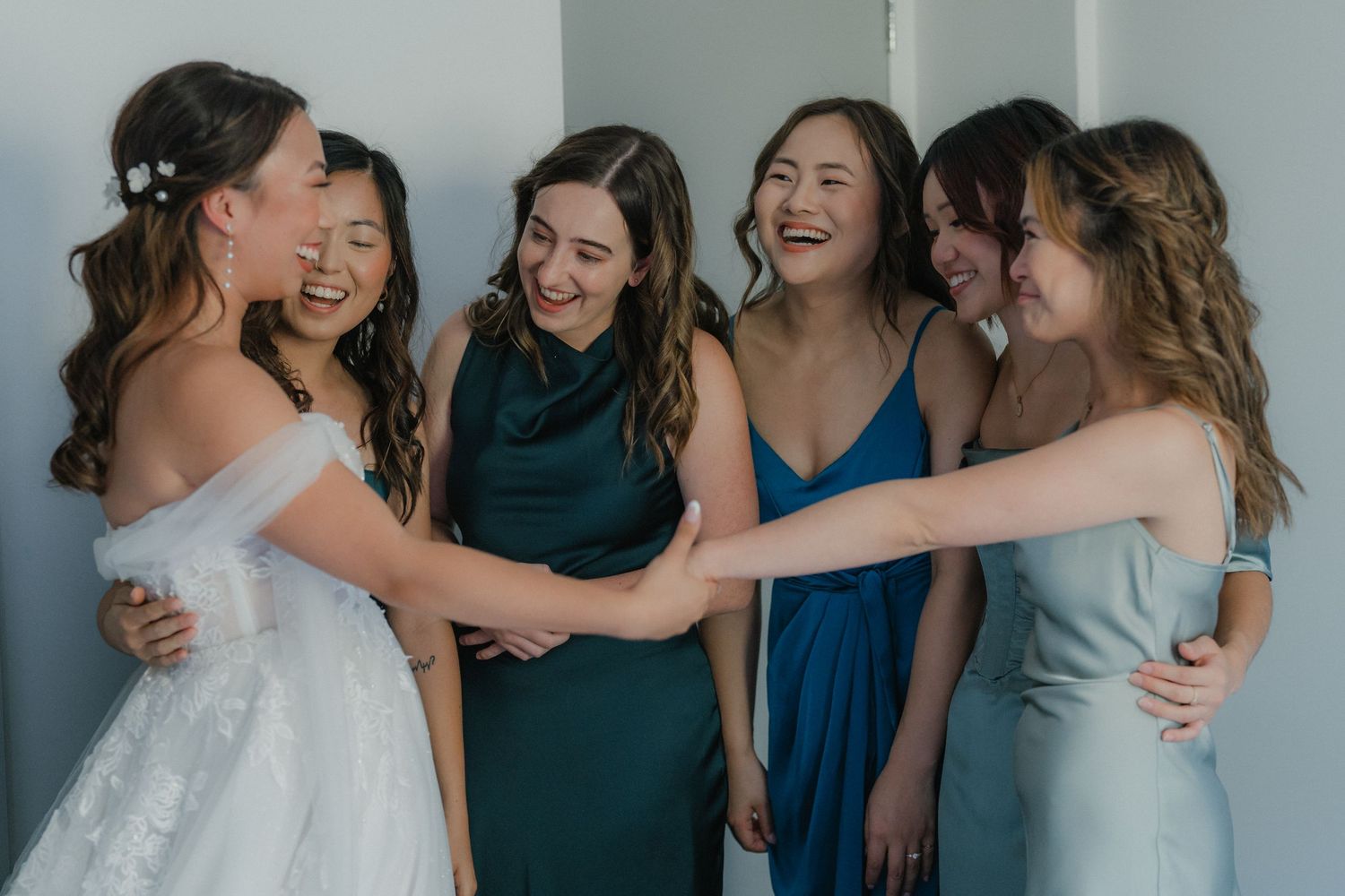 Wedding party sharing joyful moments and embracing each other in coordinated blue and white attire.