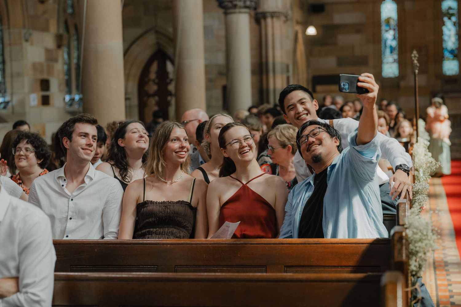 Wedding guests joyfully react while seated in church pews during a ceremony.