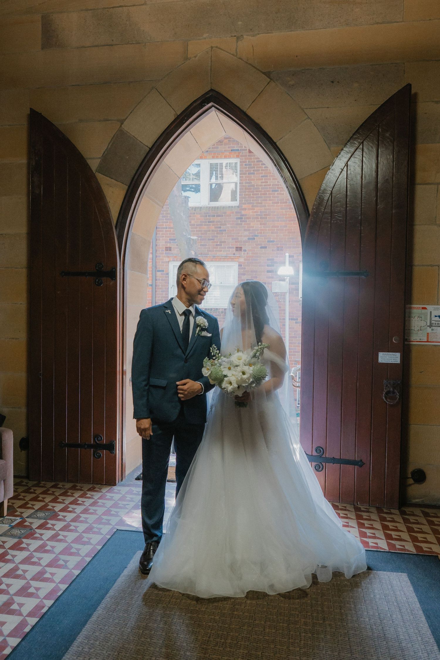 Couple poses in elegant doorway of historic church on their wedding day.