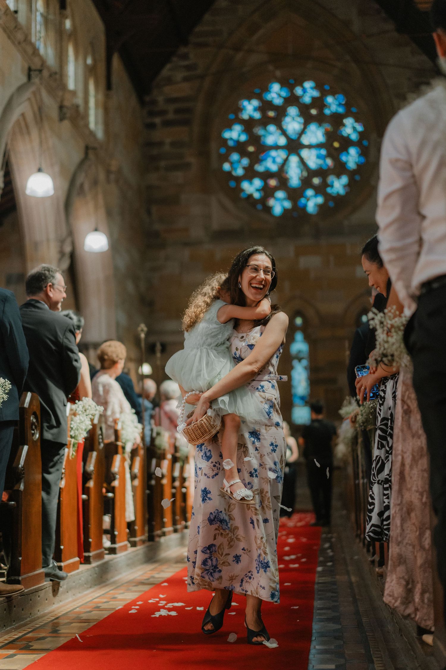 A joyful scene inside a church with a stunning blue stained glass rose window in the background.
