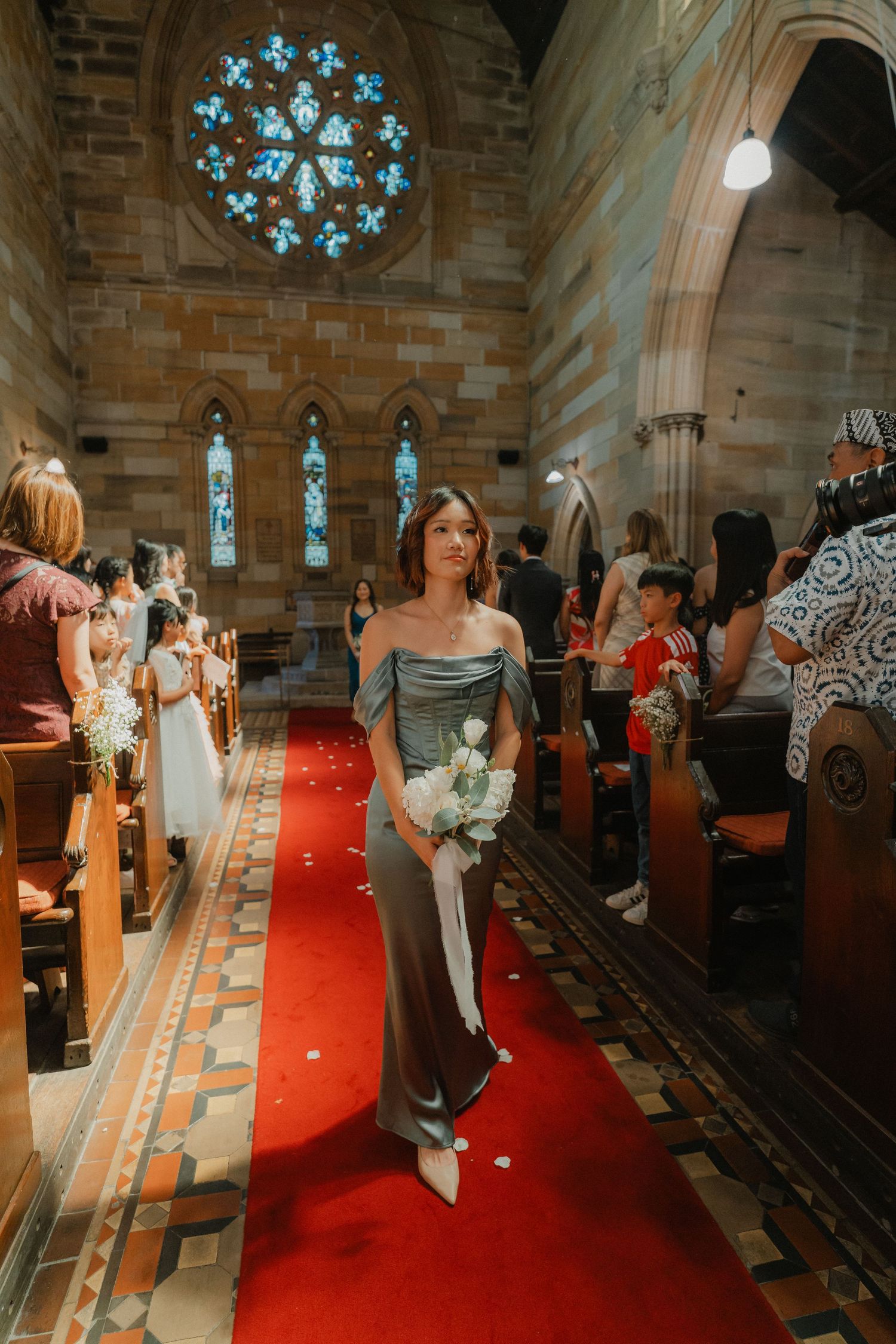 Wedding ceremony in a historic church with stone walls, stained glass windows, and guests walking down the aisle.