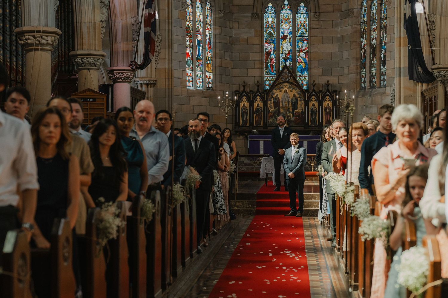 Wedding ceremony in progress inside a church with red carpet aisle.
