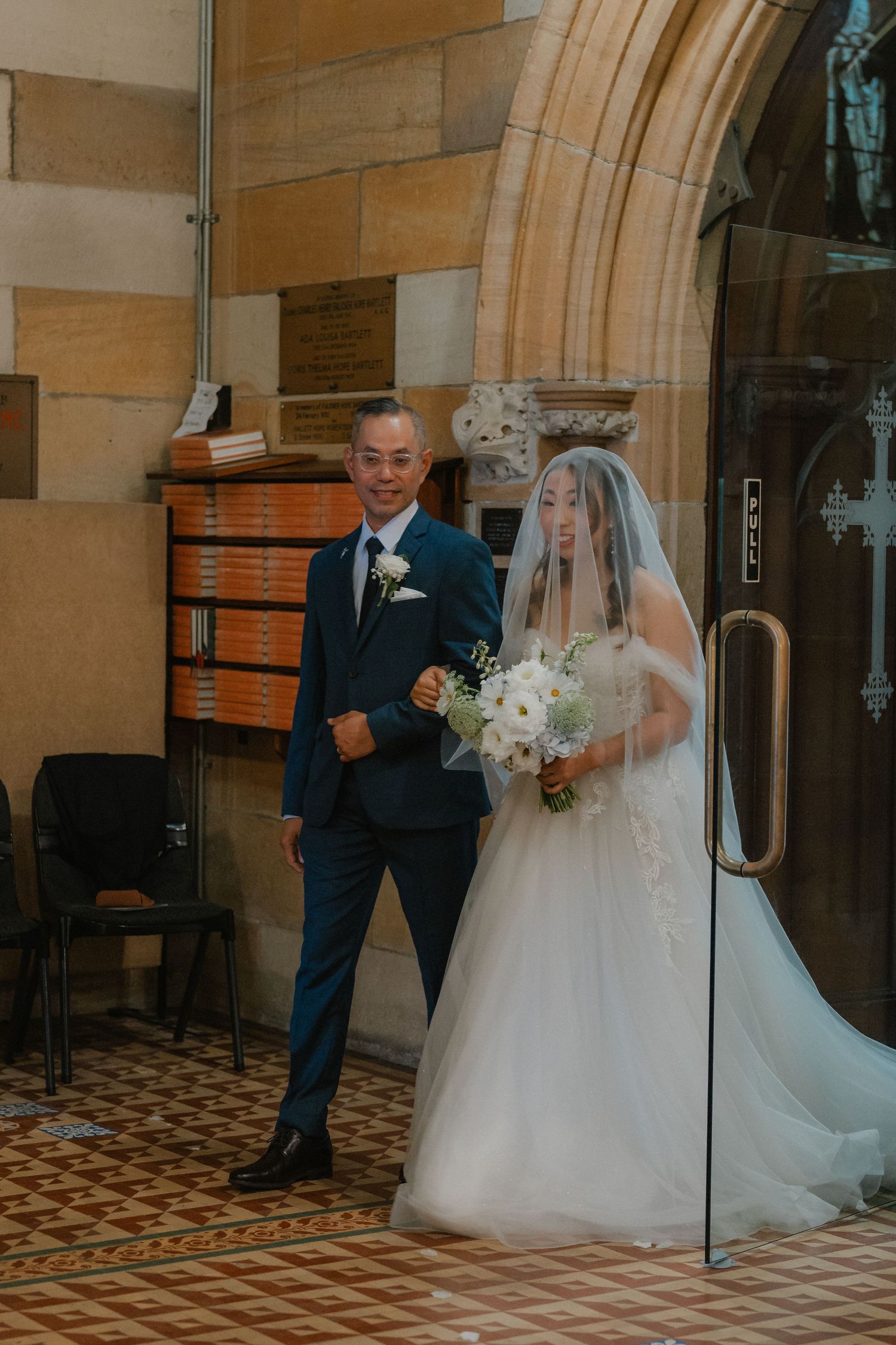 Couple stands together in formal attire inside historic church interior.