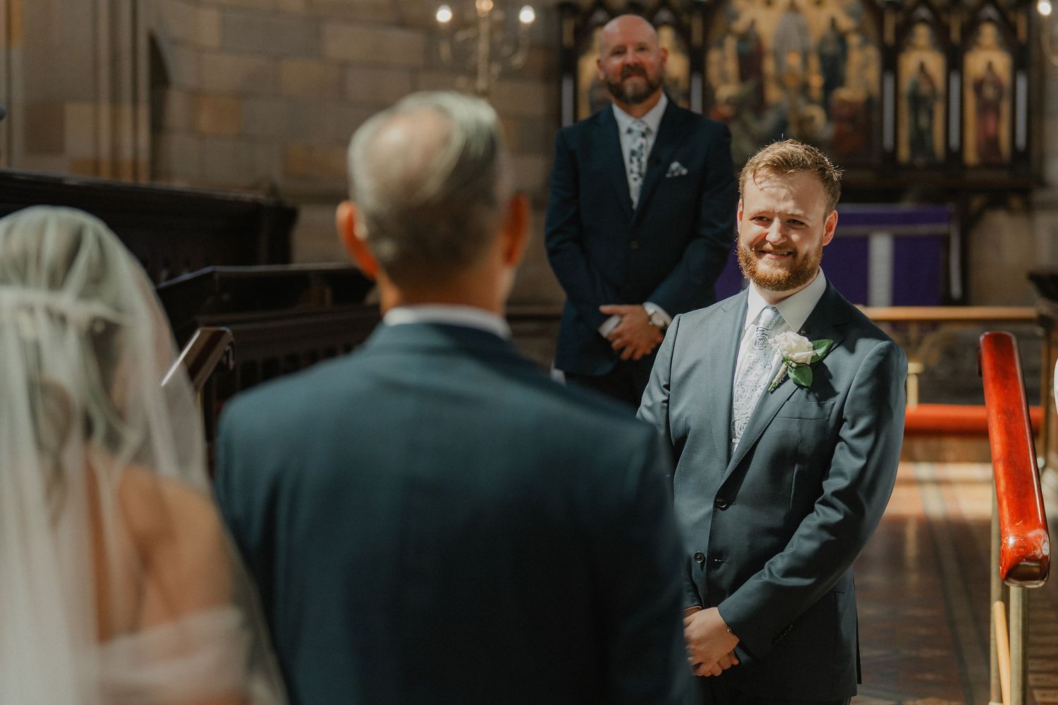 A groom shares an emotional moment at the altar in a gothic church during a wedding ceremony.