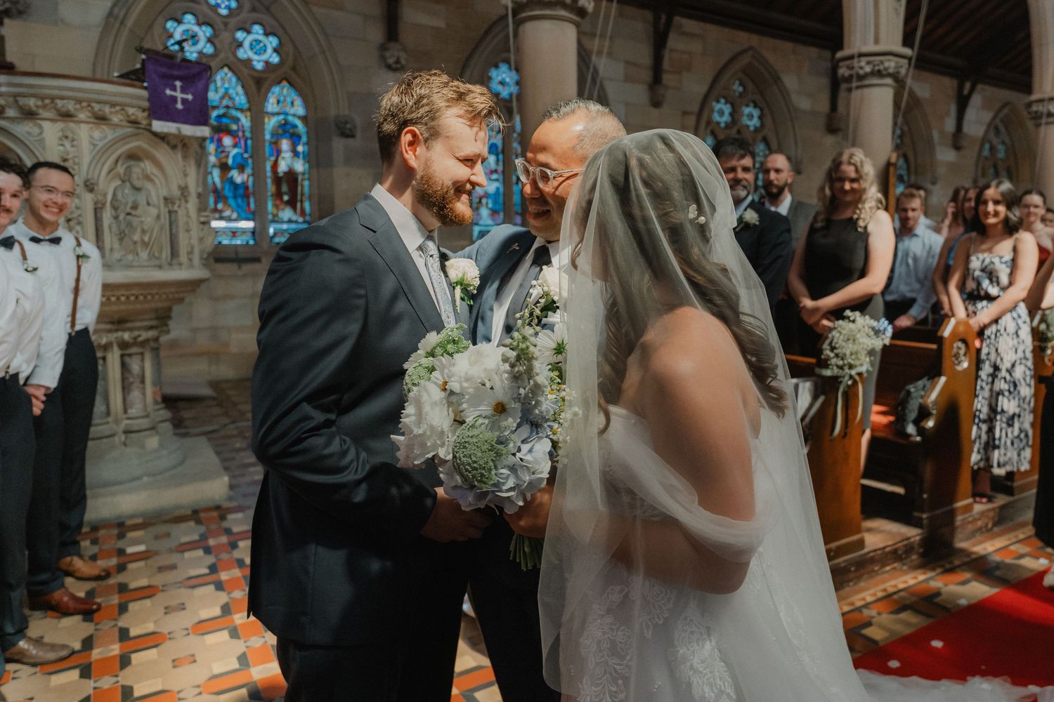 Wedding ceremony with guests watching in a traditional church setting.