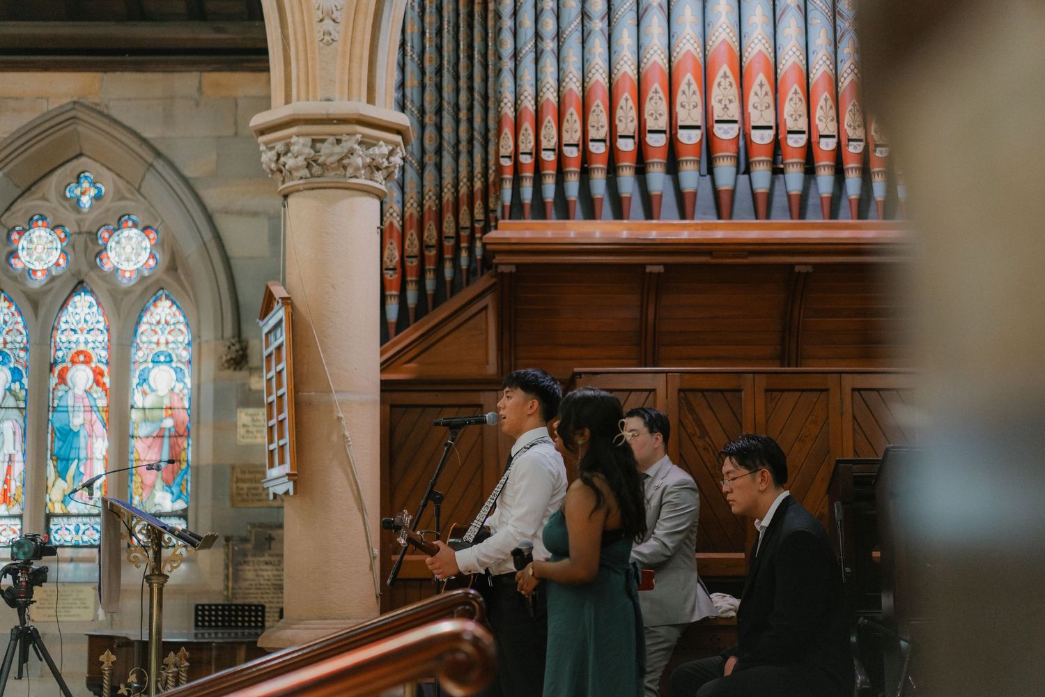 View of a church organ and stained glass windows during a wedding ceremony.