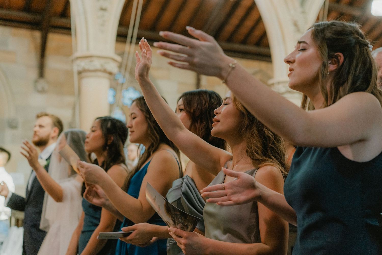 Wedding guests clapping and celebrating during a ceremony in a historic church with vaulted ceilings.